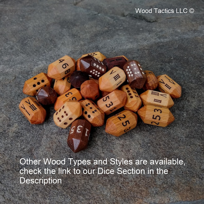 Puede incluir: Un mont&oacute;n de dados de madera con varios n&uacute;meros y n&uacute;meros romanos grabados en ellos. Los dados son de tonos marrones y madera natural. El texto "Wood Tactics LLC" es visible en la esquina superior derecha de la imagen.