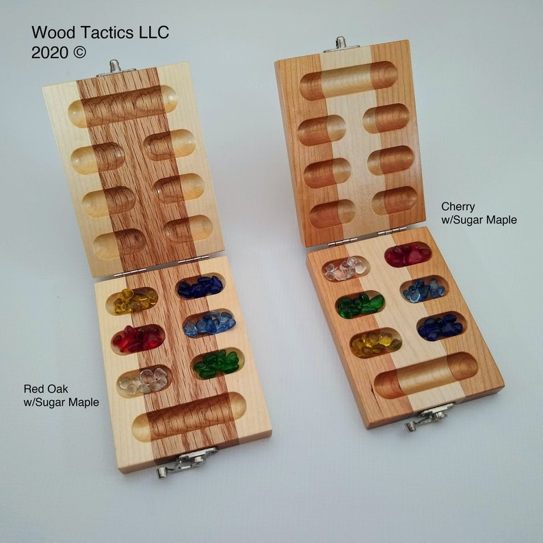 May include: Two wooden game boards with lids open, revealing colourful glass game pieces. The board on the left is made of red oak with sugar maple, and the board on the right is made of cherry with sugar maple. The text "Wood Tactics LLC 2020 &copy;" is visible at the top of the image.