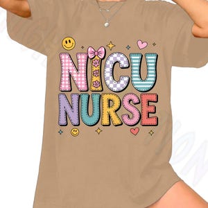 Puede incluir: Camiseta color beige con la frase "NICU NURSE" en letras coloridas estilo patchwork. El diseño incluye corazones, estrellas y caras sonrientes. La camiseta tiene un corte holgado.