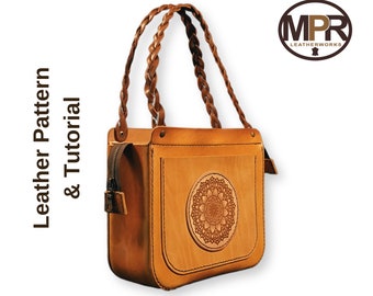 Op de afbeelding: Een bruine leren handtas met een gevlochten band en een mandala-ontwerp aan de voorkant. De tas heeft een ritssluiting en een klein vakje aan de voorkant. De tas is gelabeld met "MPR Leatherworks".