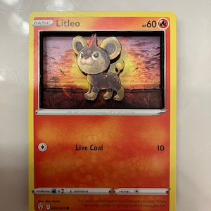 Pode incluir: Um cartão de negociação de Pokémon com Litleo, um Pokémon Filhote de Leão. O cartão é laranja e vermelho com uma imagem de Litleo no centro. O cartão tem o texto "Litleo" e "Live Coal". O cartão é número 022/203.