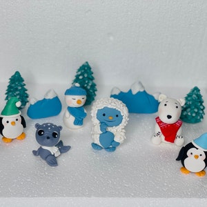 May include: A set of nine winter-themed cake toppers, including a snowman, a penguin, a polar bear, a seal, a yeti, and three pine trees. The toppers are made of fondant and are perfect for decorating a winter-themed cake.