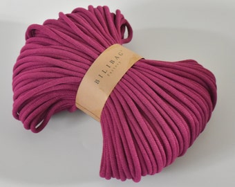 Op de afbeelding: Een close-up van een grote spoel met dieproze katoenen koord. Het koord is netjes gewikkeld en het label luidt "Billibag Factory".