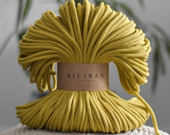 May include: A close-up of a large spool of yellow cotton rope. The rope is tightly wound and has a label that reads "Bilibag Factory".