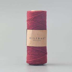 May include: A spool of deep red cotton rope with a brown label that reads "Bilibag™ Factory".
