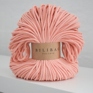 May include: A large spool of peach-coloured cotton cord, wrapped around a brown label that reads "Bilibag Factory".