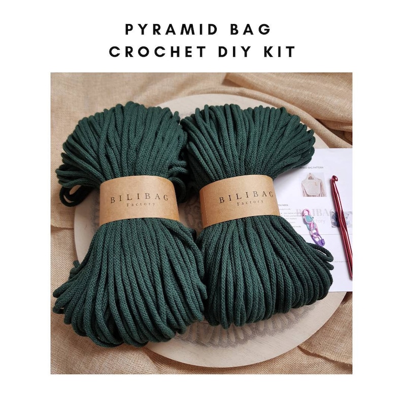 May include: A crochet DIY kit for making a pyramid bag. The kit includes two spools of dark green cotton rope, a crochet hook, and instructions. The rope is labeled "Bilibag Factory".