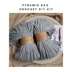 May include: A DIY crochet kit for making a pyramid bag. The kit includes two balls of gray cotton rope, a crochet hook, and instructions. The rope is labeled "Bilibag Factory".