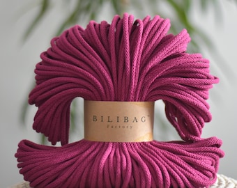 May include: A close-up of a large spool of deep pink cotton rope. The rope is tightly wound and the label on the spool reads "Bilibag Factory".