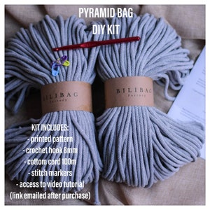 May include: A DIY kit for making a pyramid bag, including two spools of gray cotton cord, a crochet hook, stitch markers, and a printed pattern. The kit also includes access to a video tutorial.