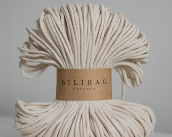 May include: A close-up of a large spool of natural cotton rope, wrapped in a brown paper label that reads "Bilibag Factory".