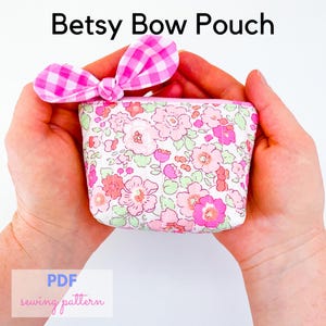 May include: A small floral pouch with a pink gingham bow, held in open hands. The pouch has a pink and white floral pattern with green accents. Text at the top reads "Betsy Bow Pouch". The bottom left corner has the text "PDF sewing pattern".