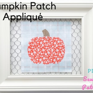 以下が含まれることがあります： 白いフレームの中に白と青の格子柄の布地が入っています。布地には、茶色の茎と白い花の模様がついた赤いカボチャのアップリケが施されています。フレームの上部には「Pumpkin Patch Applique」という文字が、右下には「PDF Sewing Pattern」という文字が書かれています。