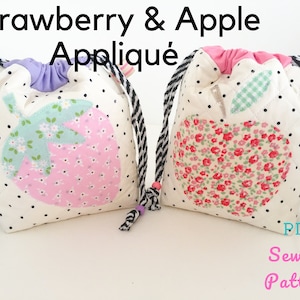 May include: Two drawstring bags with black and white striped drawstrings. One bag features a pink and green strawberry applique and the other features a red and green apple applique. Both bags have a white background with black polka dots. The text "PDF Sewing Pattern" is written in pink at the bottom of the image.