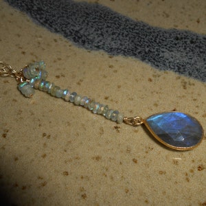 May include: A gold chain necklace with a teardrop-shaped blue labradorite gemstone pendant and a cluster of smaller iridescent stones.