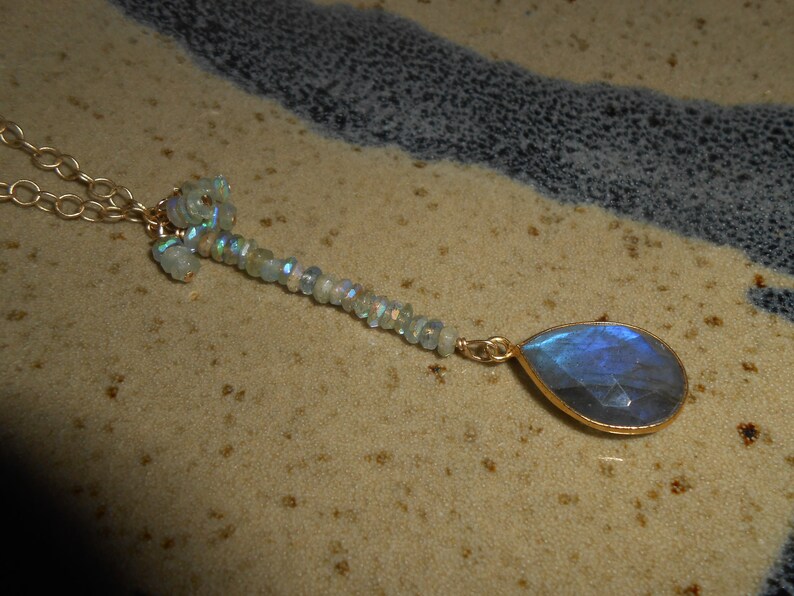 May include: A gold chain necklace with a teardrop-shaped blue labradorite gemstone pendant and a cluster of smaller iridescent stones.