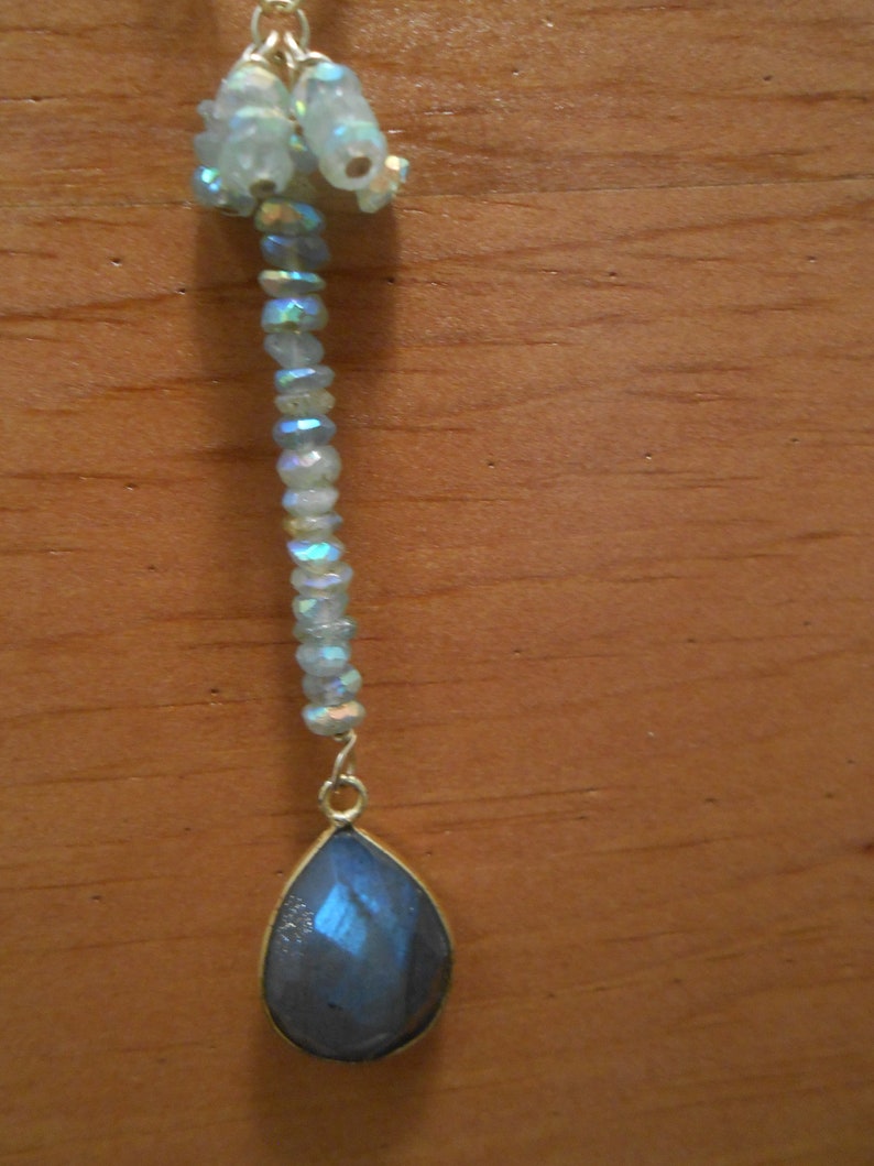May include: A teardrop-shaped pendant necklace with a blue iridescent stone and a chain of iridescent beads.