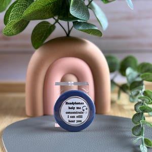 May include: A blue button with white text that reads "Headphones help me concentrate I can still hear you". A small headphone icon is next to the text.