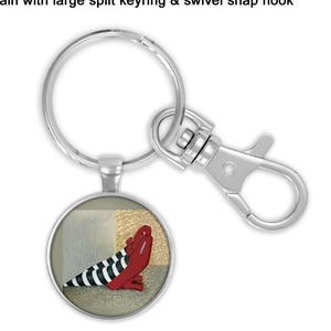 May include: Keychain with a large split keyring and swivel snap hook. The round pendant features a red shoe with black and white striped socks. The text at the top says: keychain with large split keyring & swivel snap hook.