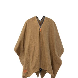Puede incluir: Un poncho de lona marr&oacute;n con cierre de cremallera y un parche de cuero. El poncho tiene cuello en V y un dise&ntilde;o largo y fluido.