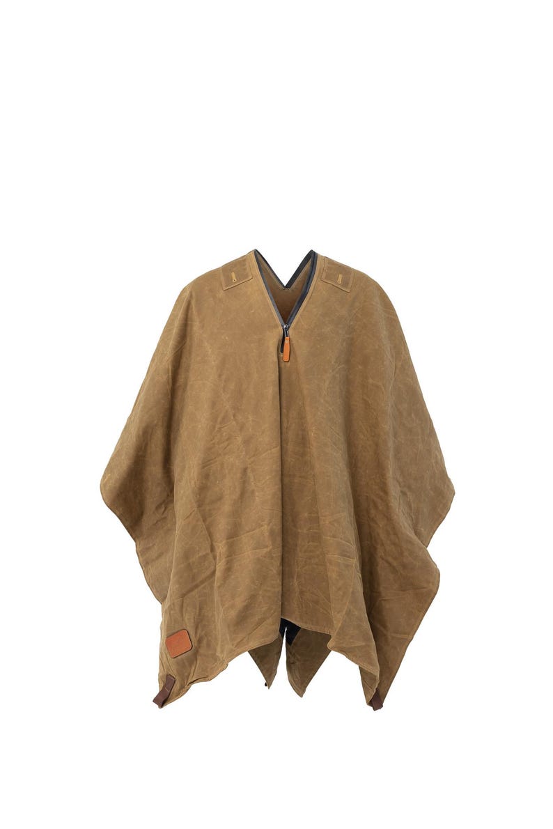 Puede incluir: Un poncho de lona marr&oacute;n con cierre de cremallera y un parche de cuero. El poncho tiene cuello en V y un dise&ntilde;o largo y fluido.