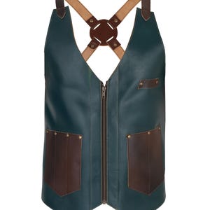 May include: A teal leather apron with brown leather accents. The apron features a full-length zipper, two front pockets, and adjustable cross-back straps. The straps are tan leather with a brown leather connector.