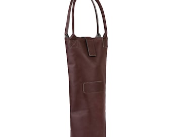 May include: A brown leather wine bottle carrier with a handle. The carrier has a rectangular patch on the front and a flap closure. The handle is attached to the top of the carrier.