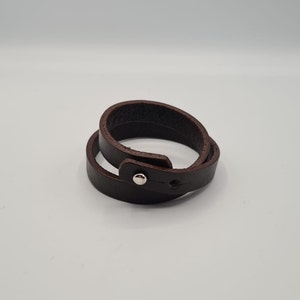 May include: A brown leather bracelet with a silver snap closure.