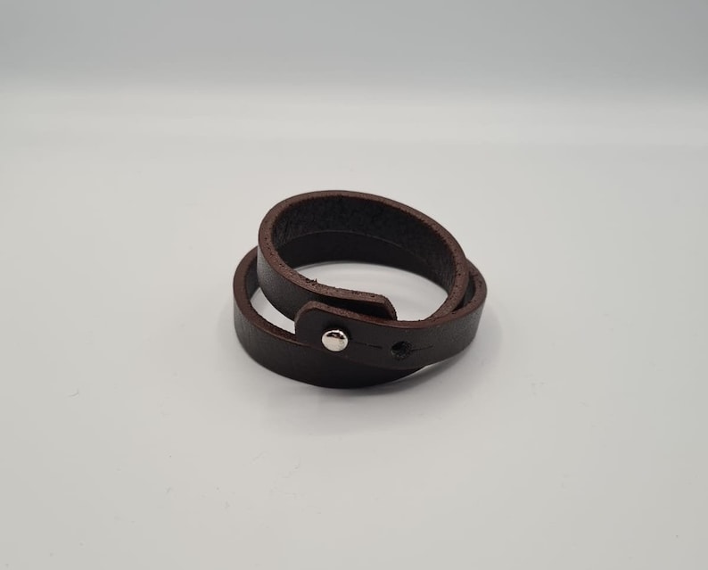 May include: A brown leather bracelet with a silver snap closure.