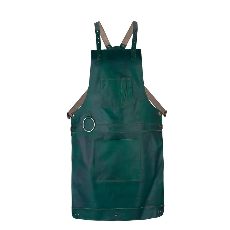 May include: A dark green leather apron featuring adjustable beige shoulder straps, a chest pocket, a large lower pocket, and a silver-toned metal ring attached to the side for hanging tools. The apron is secured with metal rivets.