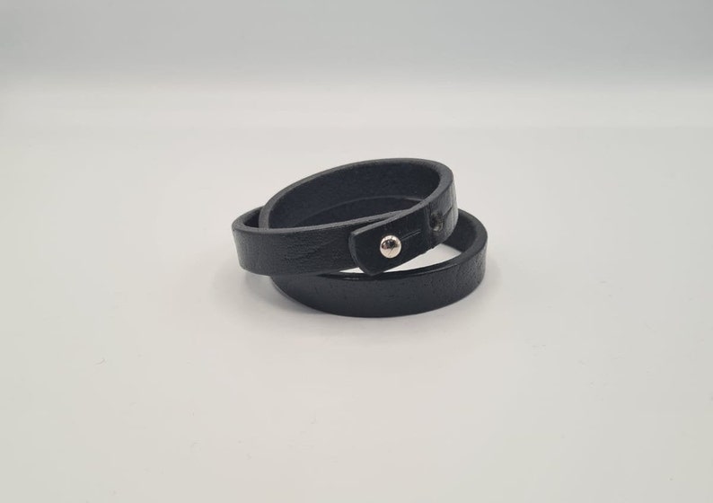 May include: A black leather wrap bracelet with a silver snap closure.