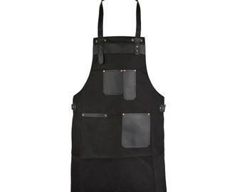 May include: Black canvas apron with multiple pockets and leather accents. The apron has adjustable straps and is secured with brass rivets.