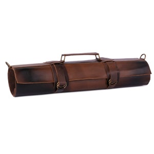 May include: A rolled-up brown leather knife bag with a handle and two straps with buckles. The leather has a gradient effect, transitioning from dark brown to a lighter shade. The bag is designed to hold knives and other kitchen tools.