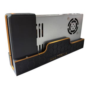 May include: A black and gold power supply holder with a silver metal power supply unit. The holder has a honeycomb pattern and the text "WWW.TTRC.US". The holder is designed to securely hold the power supply.