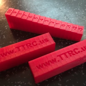 May include: Three red plastic blocks. Two blocks have the text "www.TTRC.us" printed on them. The third block has numbers 10 through 1 printed on it in descending order.