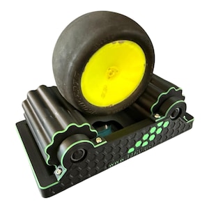 May include: Black and green RC car tire stand with a black tire and yellow rim. The stand has a honeycomb pattern and the text "www.ftrc.us". The stand has green accents.