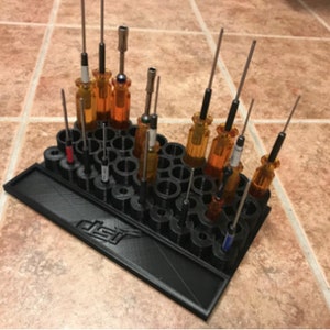 May include: Black plastic screwdriver holder with 30 slots, filled with various screwdrivers with orange handles. The holder has the text "DSI" printed on the bottom.
