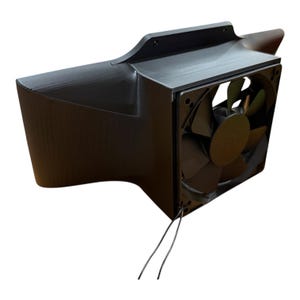 May include: A black, rectangular computer fan with a curved housing. The fan has a square frame and a central fan blade. Two black wires extend from the fan.