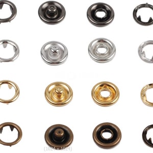 May include: Assortment of 12 metal snap fasteners in various finishes, including silver, gold, bronze, and black. The fasteners are round and have a raised centre with a small hole in the middle. They are commonly used for clothing, crafts, and other projects.