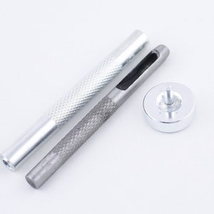 May include: A set of three silver metal tools for leather crafting. The tools include a punch, a hammer, and a handle.