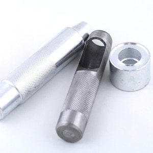 May include: A set of three silver metal tools for punching holes in leather. The tools include a punch, a hollow punch, and a setting tool.
