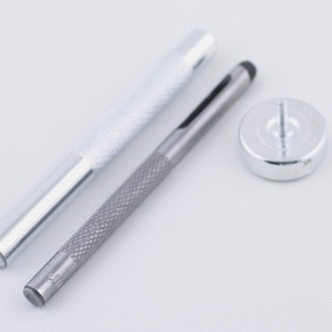May include: A set of three silver tools for leather crafting. The tools include a hollow punch, a hammer, and a setting tool.