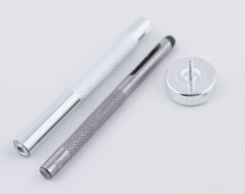 May include: A set of three silver tools for leather crafting. The tools include a hollow punch, a hammer, and a setting tool.