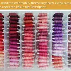 May include: A clear plastic organizer filled with rows of colorful embroidery floss. The floss is organized by color, with shades of red, pink, purple, and brown.
