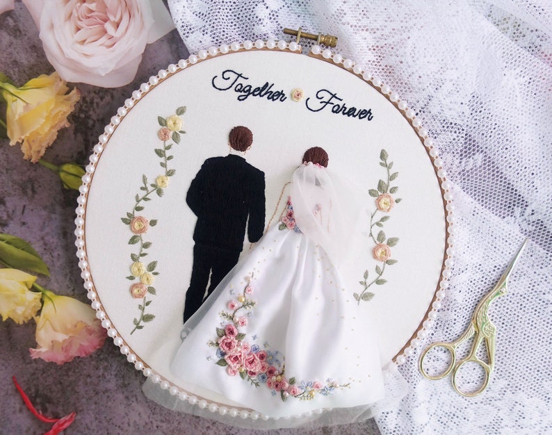 Pu&ograve; includere: Arte di ricamo a cerchio con una sposa e uno sposo in bianco e nero, con dettagli floreali e il testo "Together Forever".