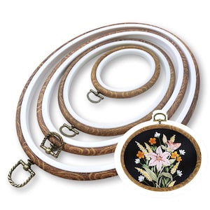 Peut inclure: Un ensemble de quatre tambours à broder ovales emboîtables avec un motif de grain de bois brun et des anneaux intérieurs blancs, dotés de vis de serrage en laiton antique. Un tambour contient un tissu noir brodé de fleurs roses, orange et blanches.