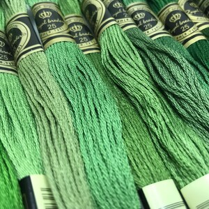 May include: A close-up of multiple spools of green embroidery floss. The spools are labeled "Royal Brode" and "25".