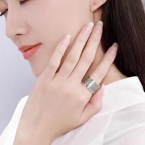 Puede incluir: Un anillo de plata con un dise&ntilde;o intrincado. El anillo se lleva en el dedo &iacute;ndice de una mano.