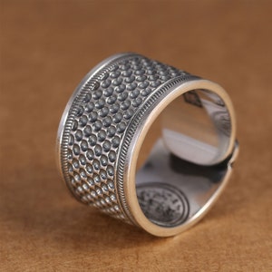 Puede incluir: Un anillo de plata con un acabado texturizado martillado. El anillo es ancho y tiene una banda redondeada.