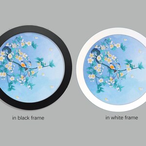 May include: A round embroidery depicting two blue birds perched on a branch with white blossoms against a blue watercolor background. The embroidery is framed in black and white.